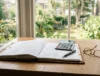 Carpeta, calculadora y gafas sobre un escritorio, tabla de la pensión compensatoria